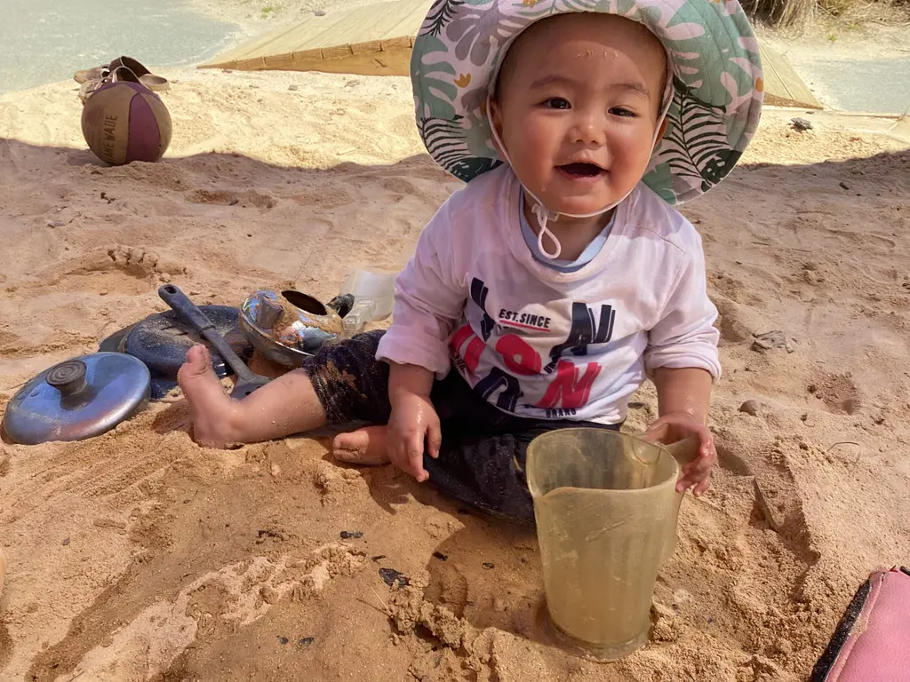 A smiling toddler exploring in the sandpit